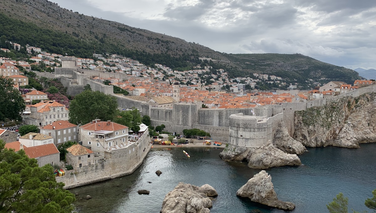 View of Cavtat's harbour at dusk with traditional stone buildings reflected in still water