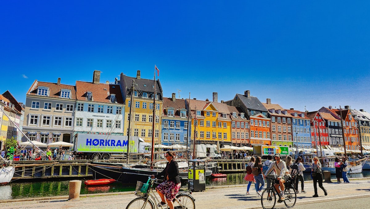 Nyhavn canal lined with colourful 17th-century merchant houses and wooden sailing boats on a sunny afternoon