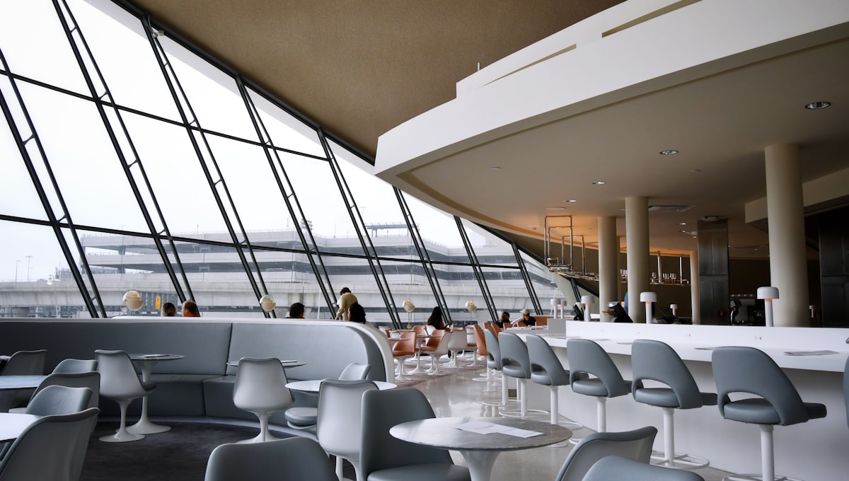Passenger in an airline lounge with floor-to-ceiling windows overlooking an airport apron