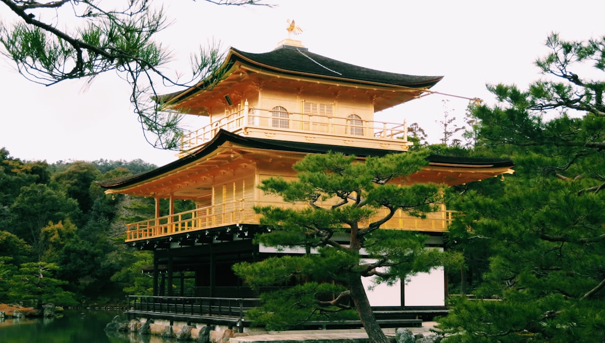 Snow-dusted Kinkaku-ji temple reflected in the still water of the surrounding pond in winter