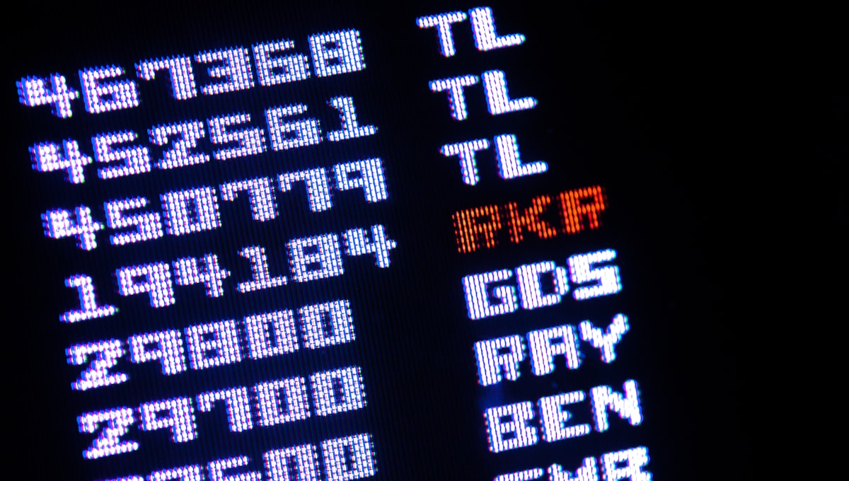 Person comparing flight prices on laptop and mobile phone simultaneously