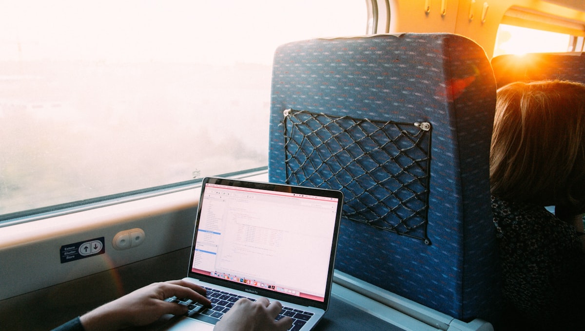 person using macbook pro on blue and white chair