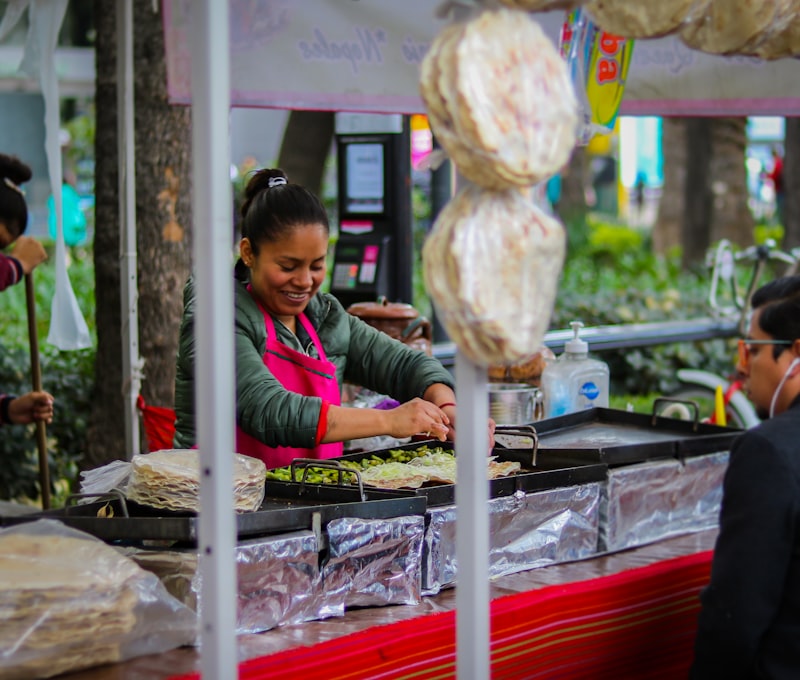 Mexico City street food taco stand at night with tacos al pastor on vertical spit and a queue of locals