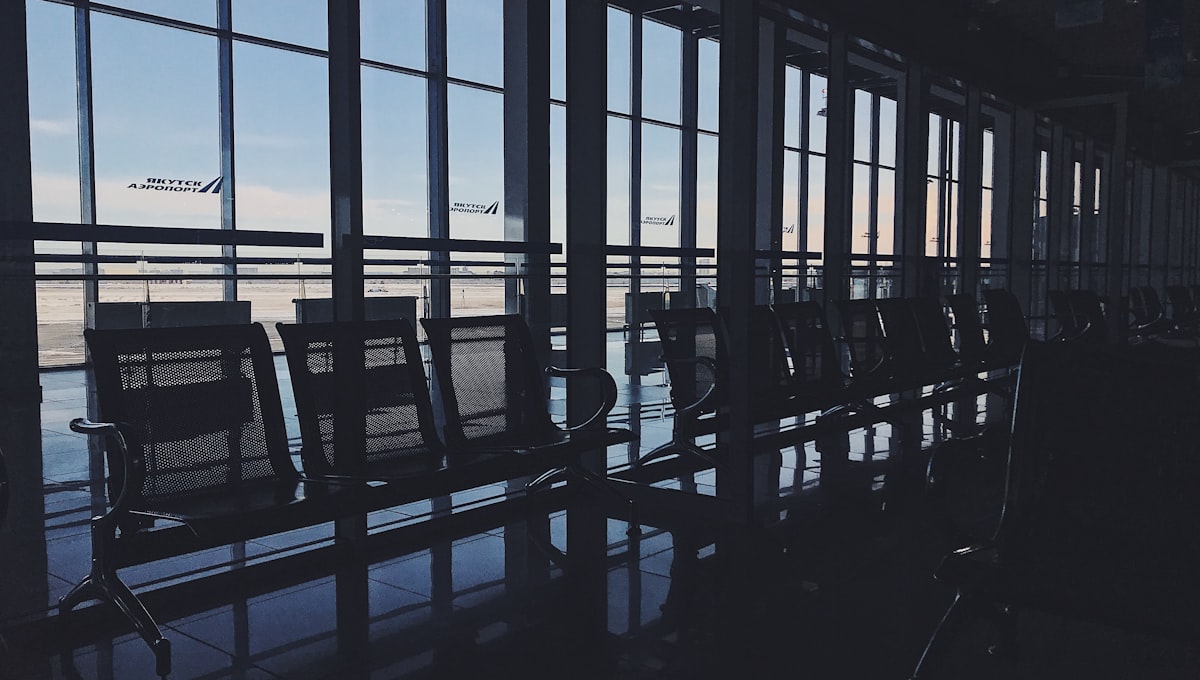 Empty airport departure lounge with flight information screens showing cancellations